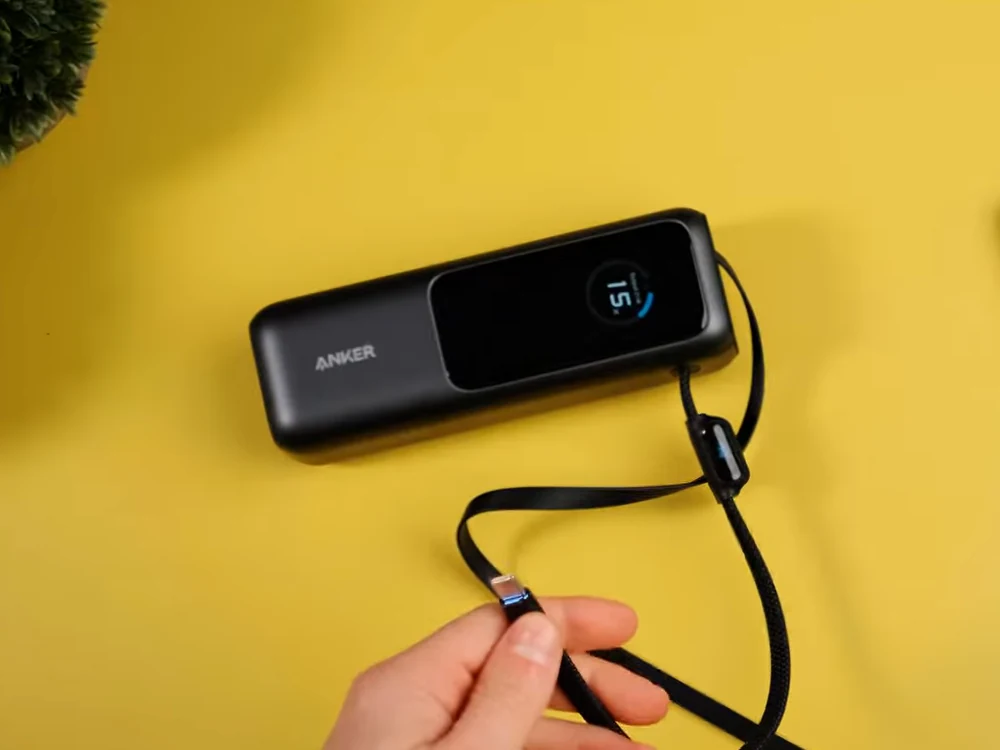 The Anker A1695 power bank and its retractable cable, filmed against a yellow background